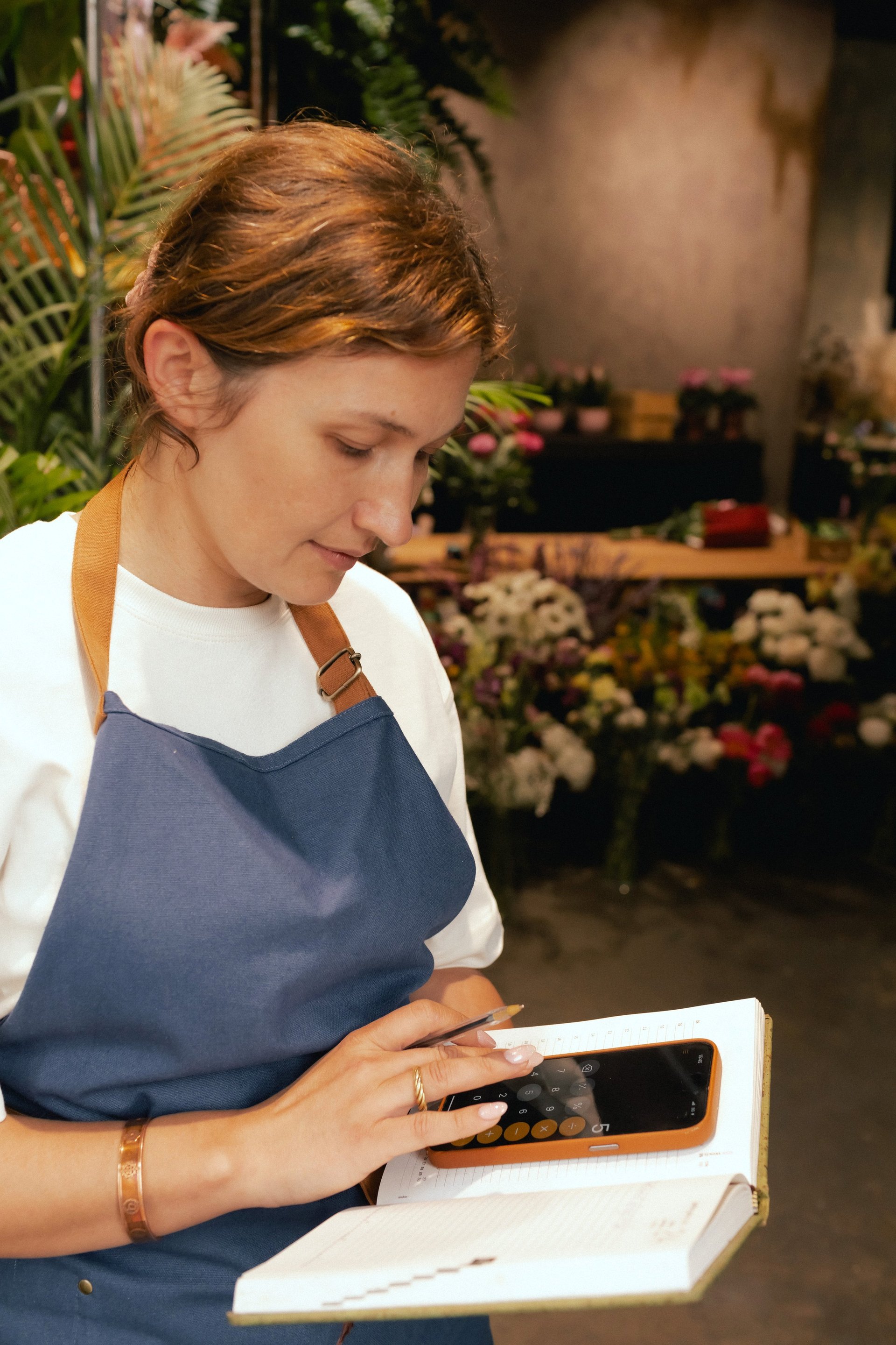 Female florist in apron arranging flowers at flower shop
